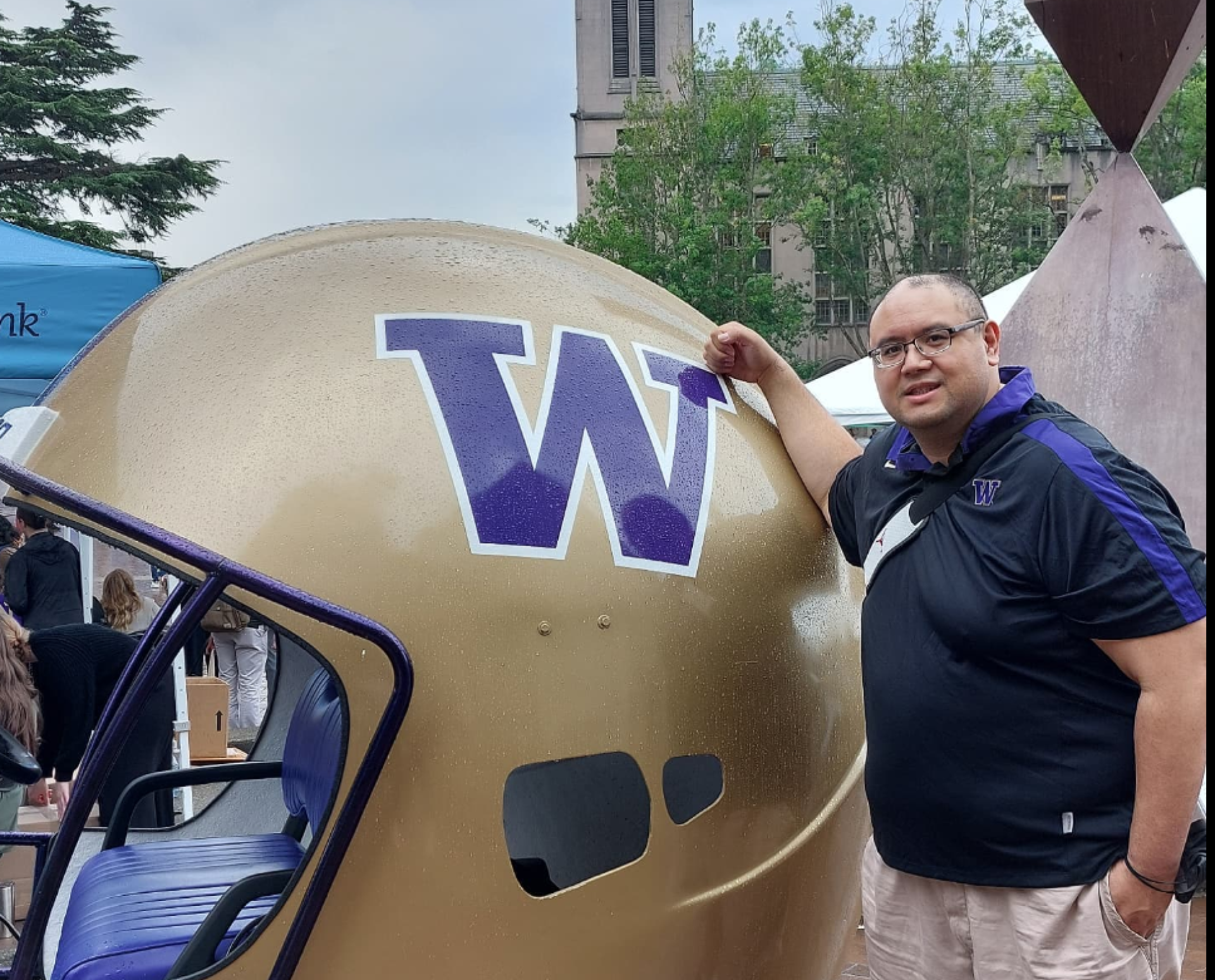 Jeremiah Cruz stands next to an oversized Husky football helmet